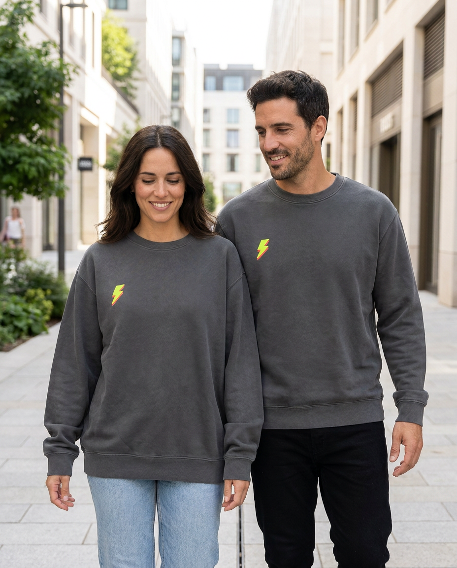 Foto de un chico y una chica llevando la sudadera básica unisex de algodón orgánico color gris antracita con detalle de rayo minimalista en el pecho color verde ácido de la marca Zander. 